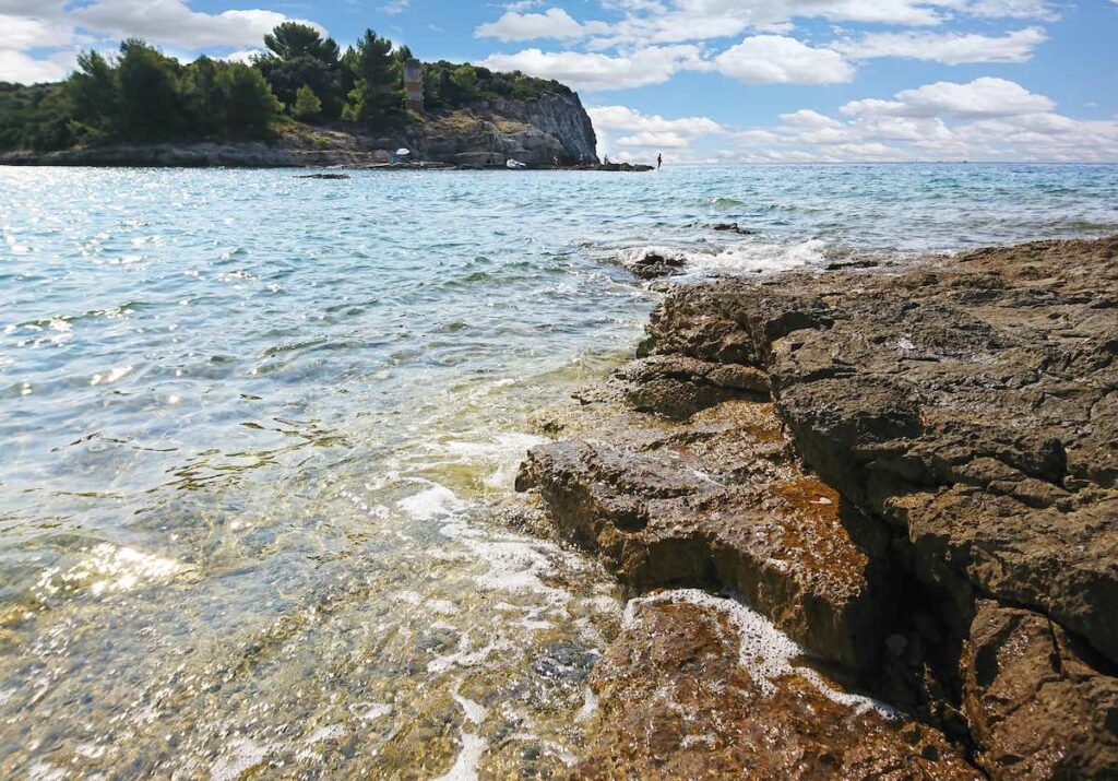 Spiaggia Pola con acqua limpida e costa rocciosa tipica dell’Istria