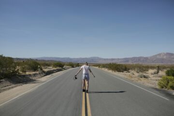 Viaggiatore con zaino che fa autostop su una strada aperta