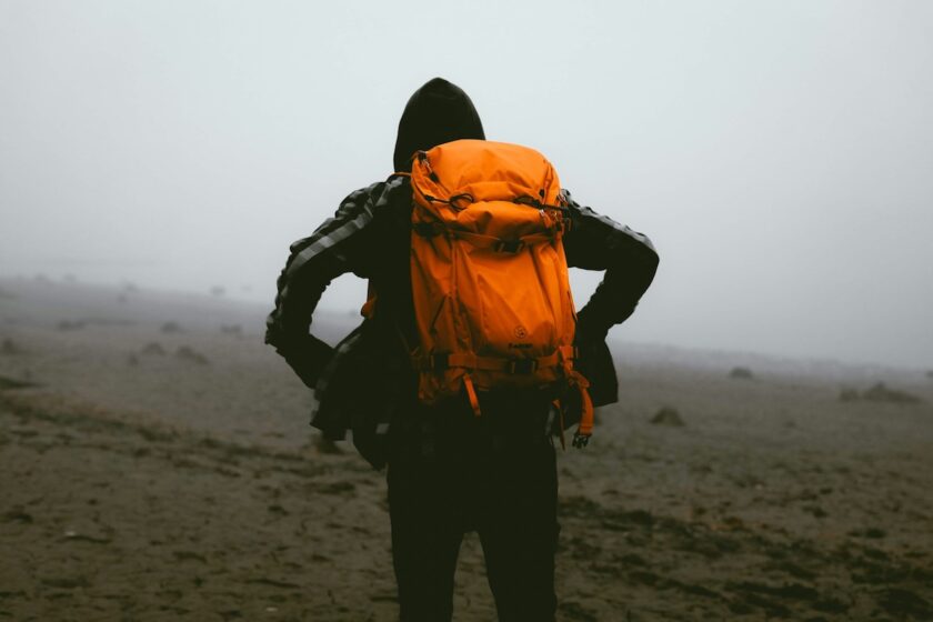 Viaggiatore solitario con zaino guarda il paesaggio dall’alto