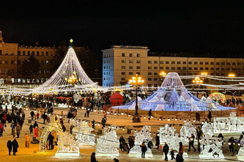 Bancarelle illuminate del mercatino di Natale a Vilnius con neve e persone che passeggiano