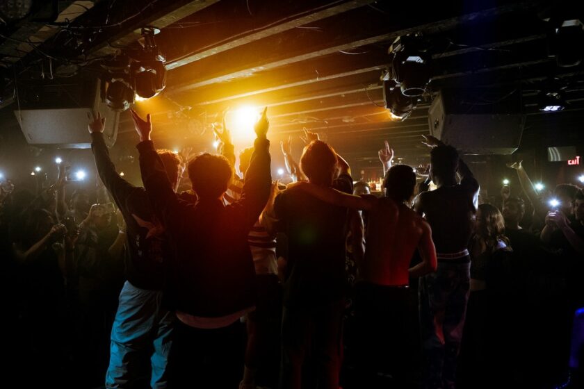 Giovani che ballano in una discoteca di Varsavia tra luci colorate e musica.