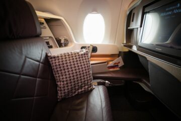 Sedile di business class con televisore e finestrino illuminato in un aereo moderno