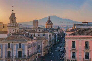 Vista del centro storico di Catania con palazzi barocchi e l’Etna innevata sullo sfondo