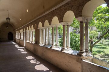 Chiostro di abbazia nel Lazio con archi in pietra e luce naturale