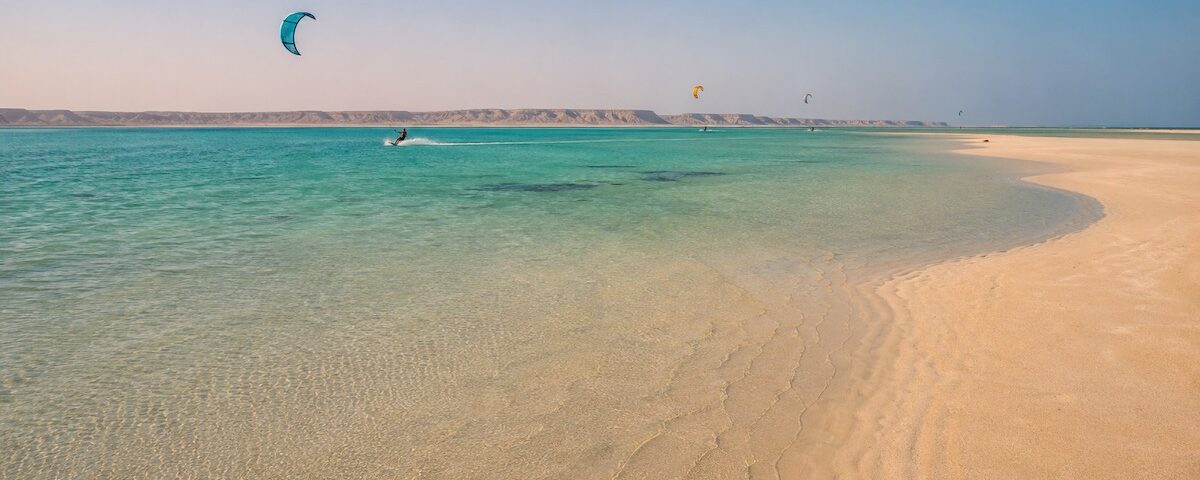 Laguna turchese in Oman con vele da kitesurf in lontananza