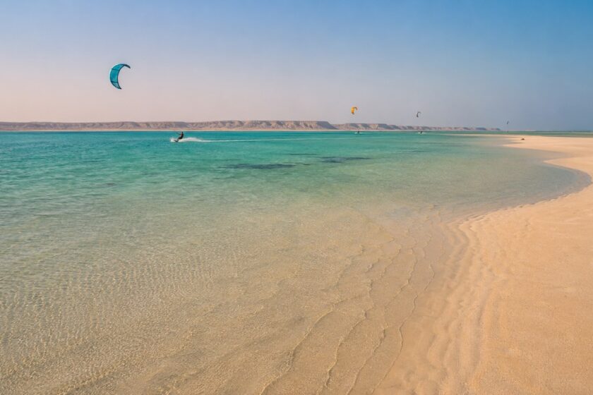 Laguna turchese in Oman con vele da kitesurf in lontananza