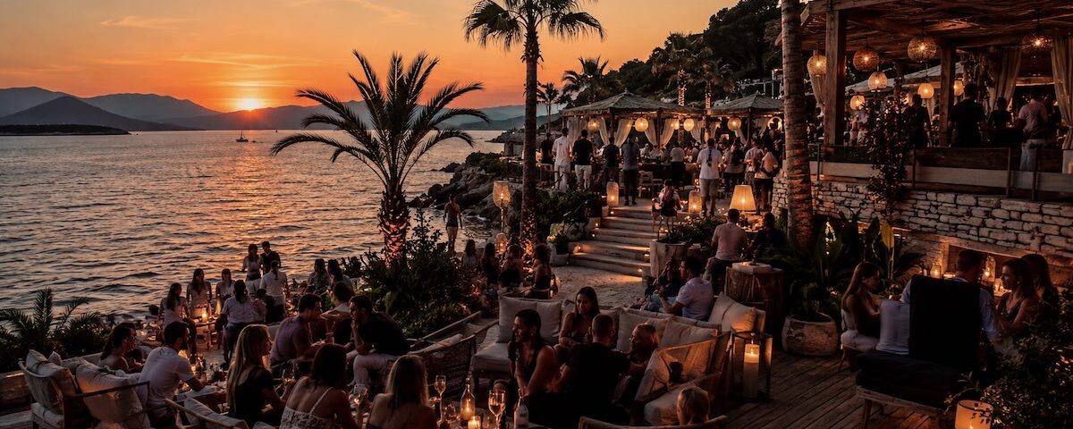 Beach club sulla costa croata al tramonto con giovani e mare sullo sfondo