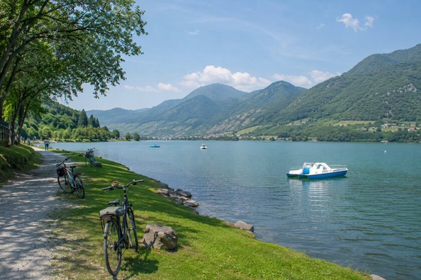 Passeggiata lungo il Lago di Endine con prati verdi, pedalò sull’acqua e montagne della Val Cavallina