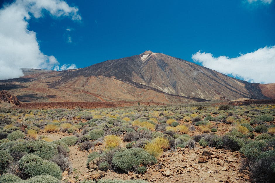 A panoramic view of Tenerife in December, with sunny beaches, vibrant city lights, and the imposing Mount Teide in the background. Enjoy a warm winter getaway in Tenerife.